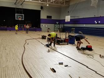 Workers sanding the new wood floor.